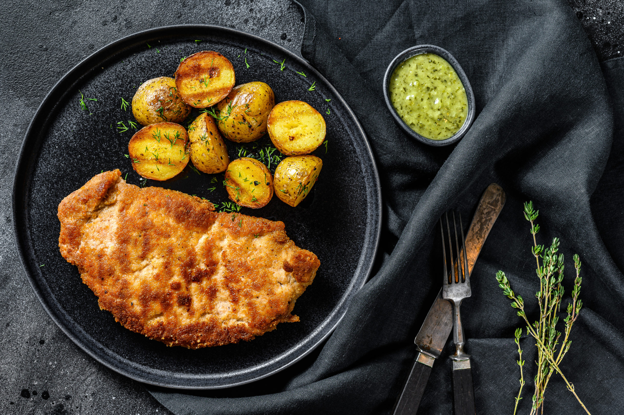 Fried Chicken schnitzel with baked potatoes. Black background